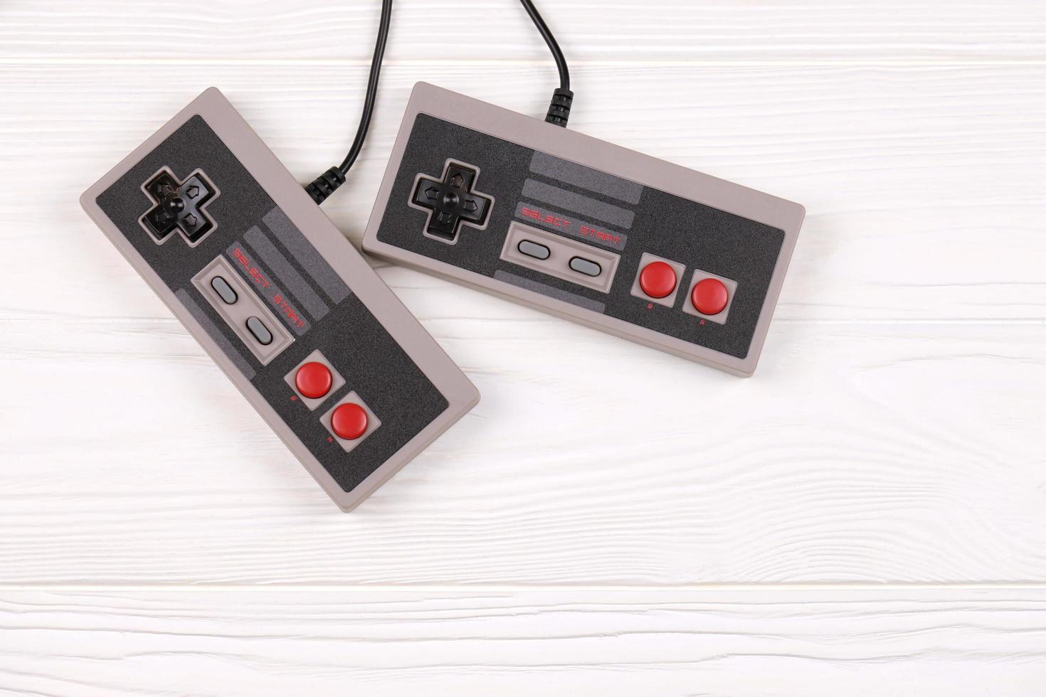KHARKOV, UKRAINE - DECEMBER 27, 2020 Two old gamepads for 8-bit video game consoles nintendo entertainment system and nes mini on white table. Old school retro gaming photo