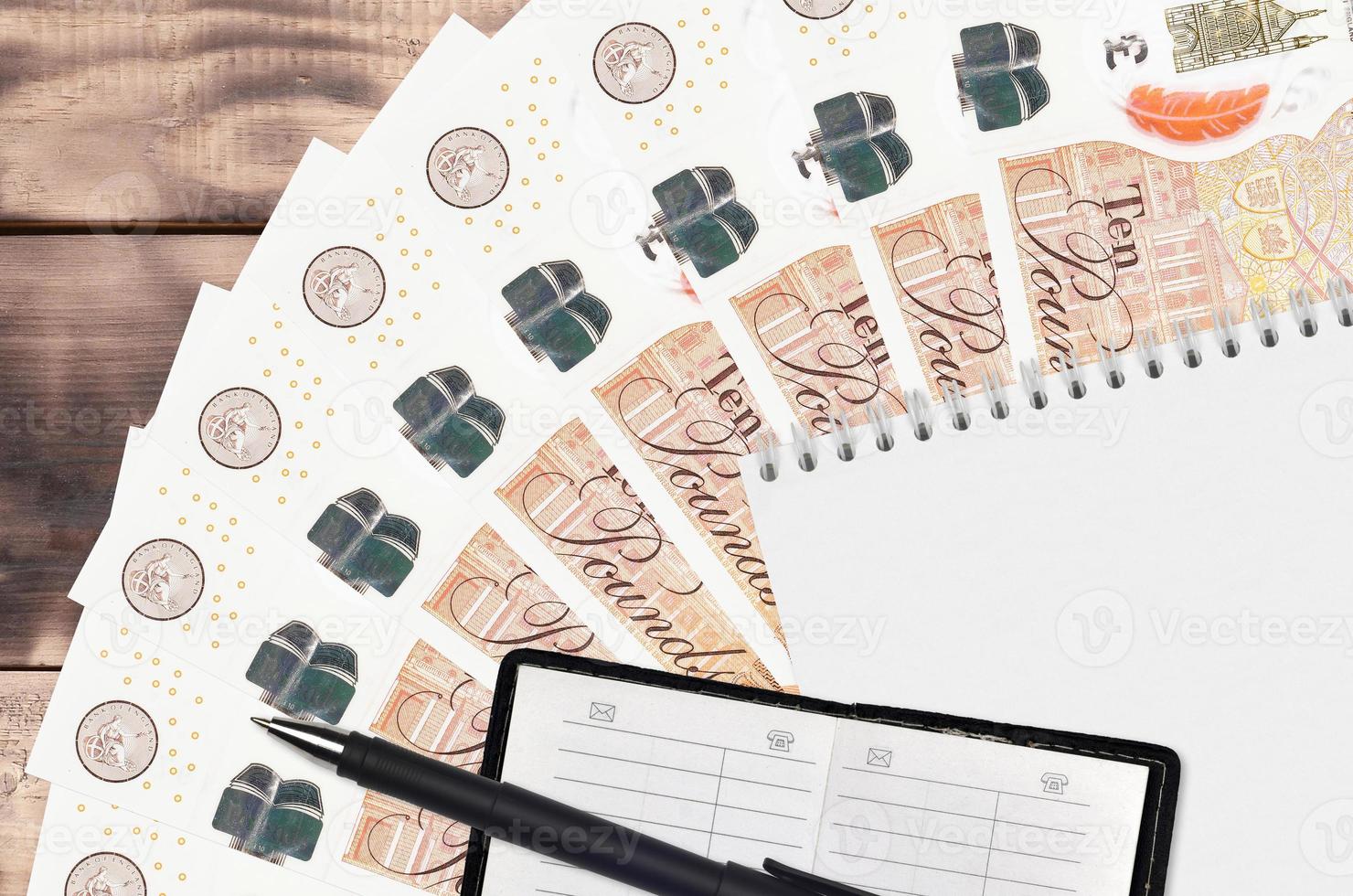 10 British pounds bills fan and notepad with contact book and black pen. Concept of financial planning and business strategy photo
