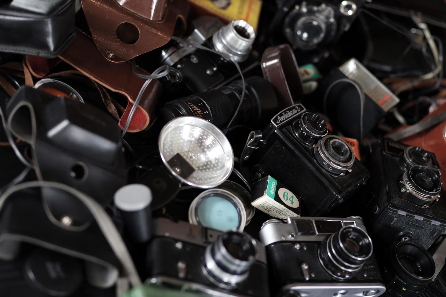 KHARKOV, UKRAINE - APRIL 27, 2021 Film photo cameras and another old retro photo equipment on black wooden table in photographer darkroom. Photographic gear from soviet union