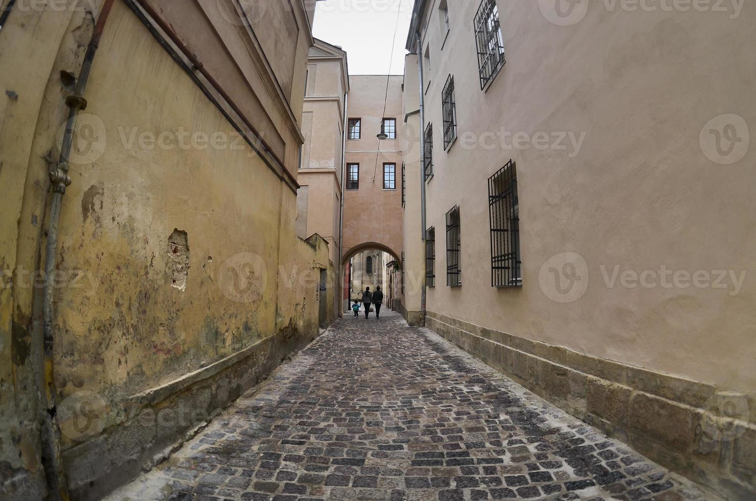 calle estrecha con un camino de adoquines. pasaje entre los antiguos edificios históricos de gran altura en lviv, ucrania foto