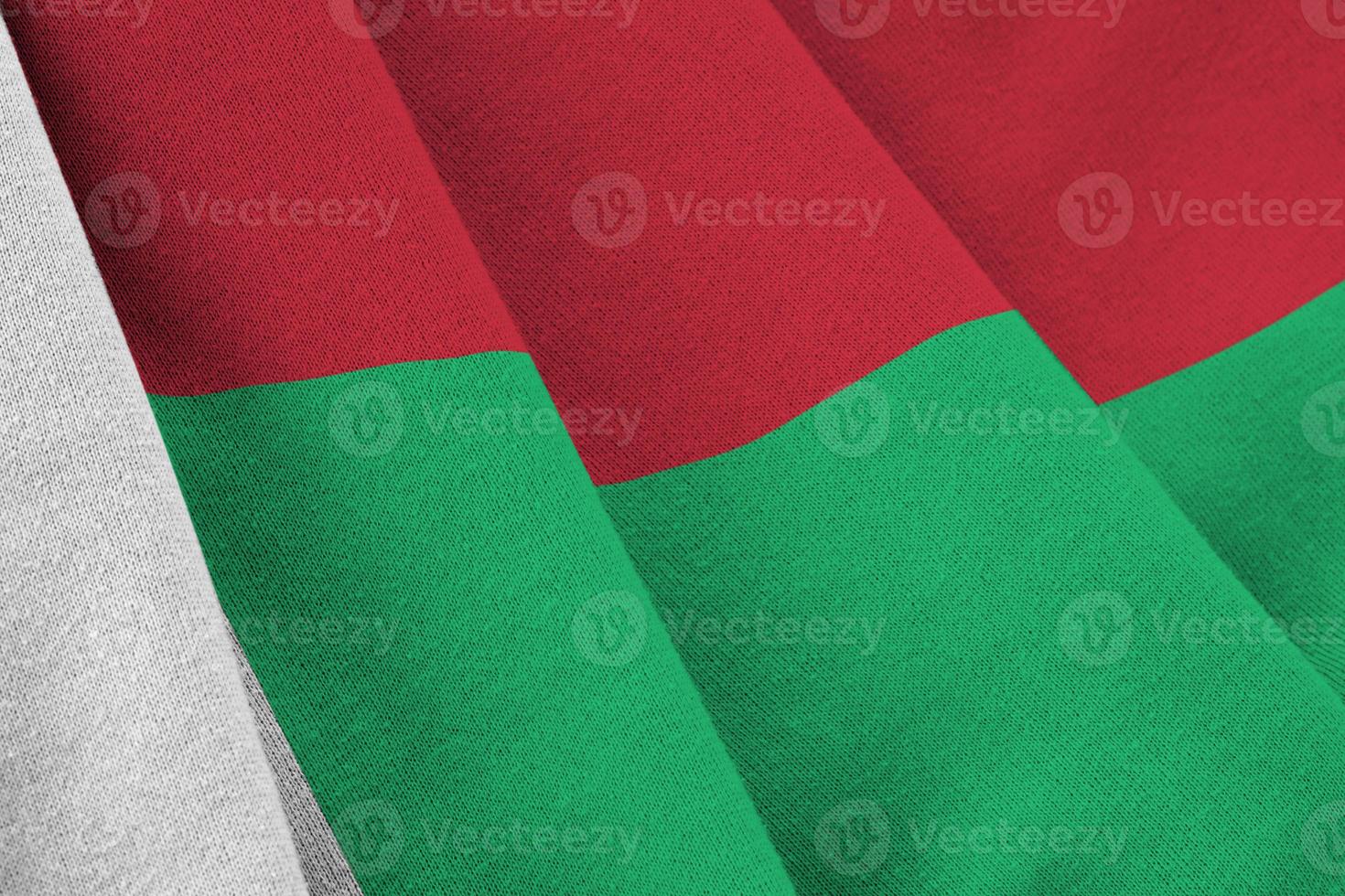 Madagascar flag with big folds waving close up under the studio light indoors. The official symbols and colors in banner photo