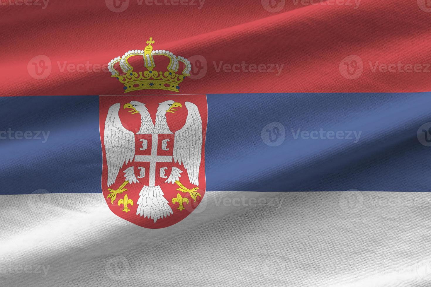 bandera serbia con grandes pliegues ondeando de cerca bajo la luz del estudio en el interior. los símbolos y colores oficiales en banner foto