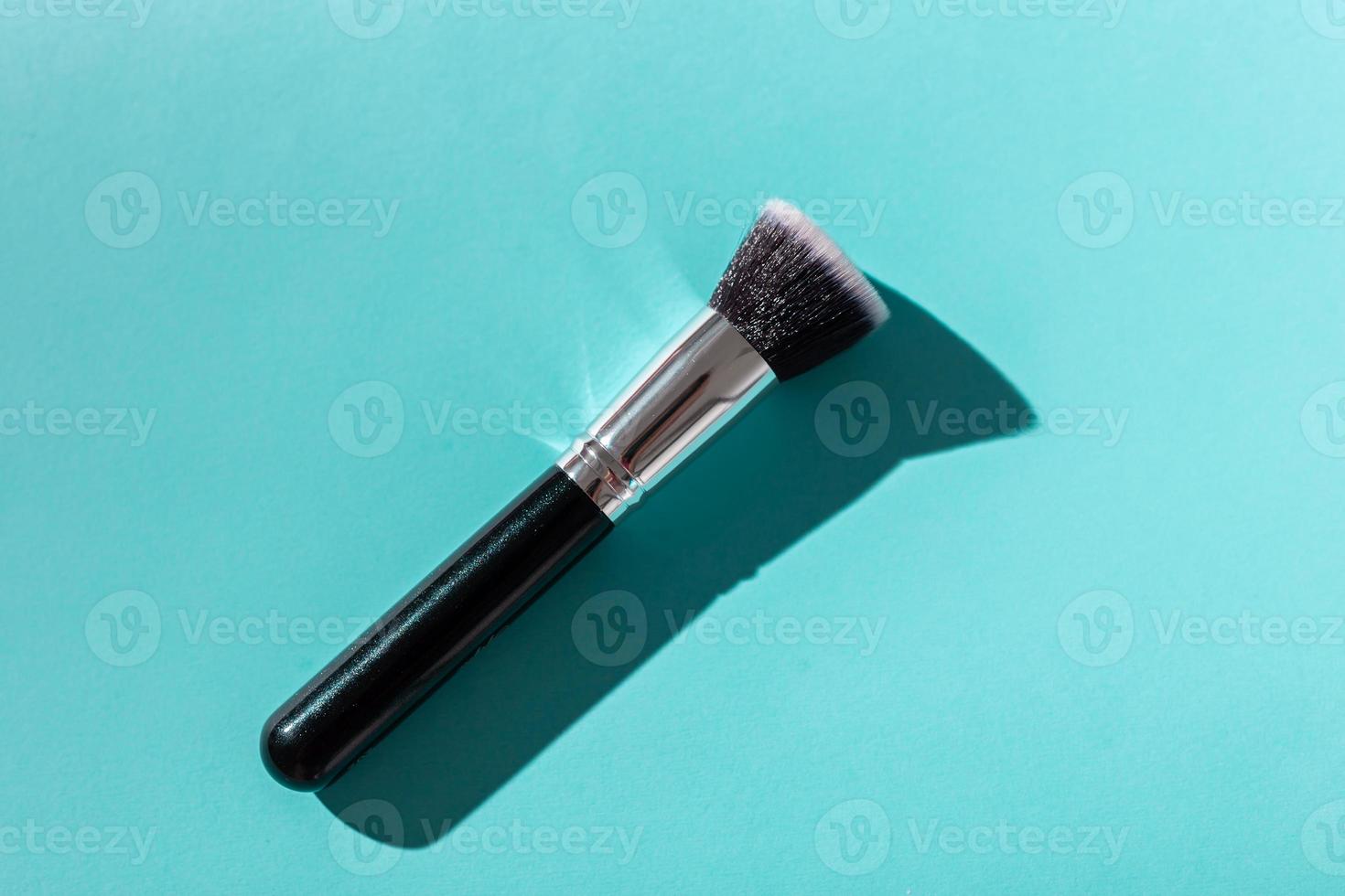 Make up brush on turquoise background, top view. photo