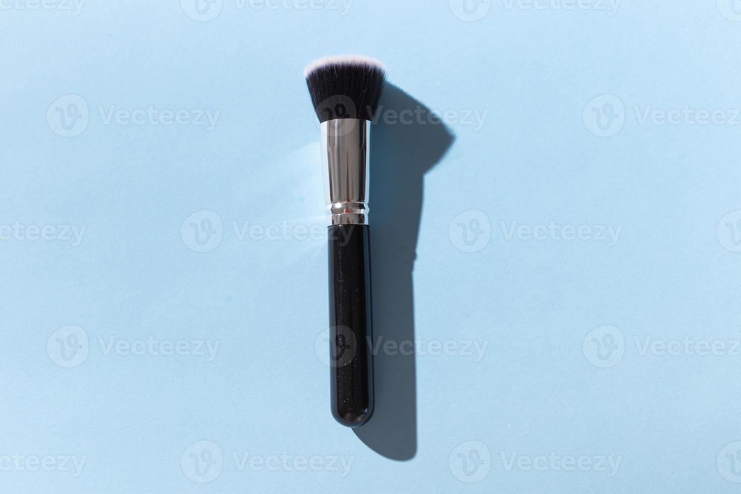 Make up brush on blue background, top view. photo