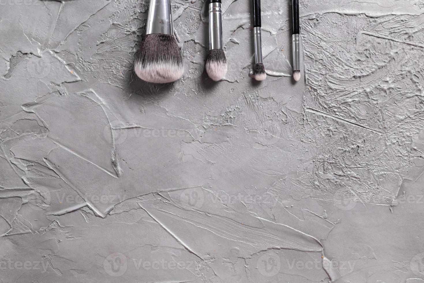 Top view of make-up brushes on grey background with copyspace photo