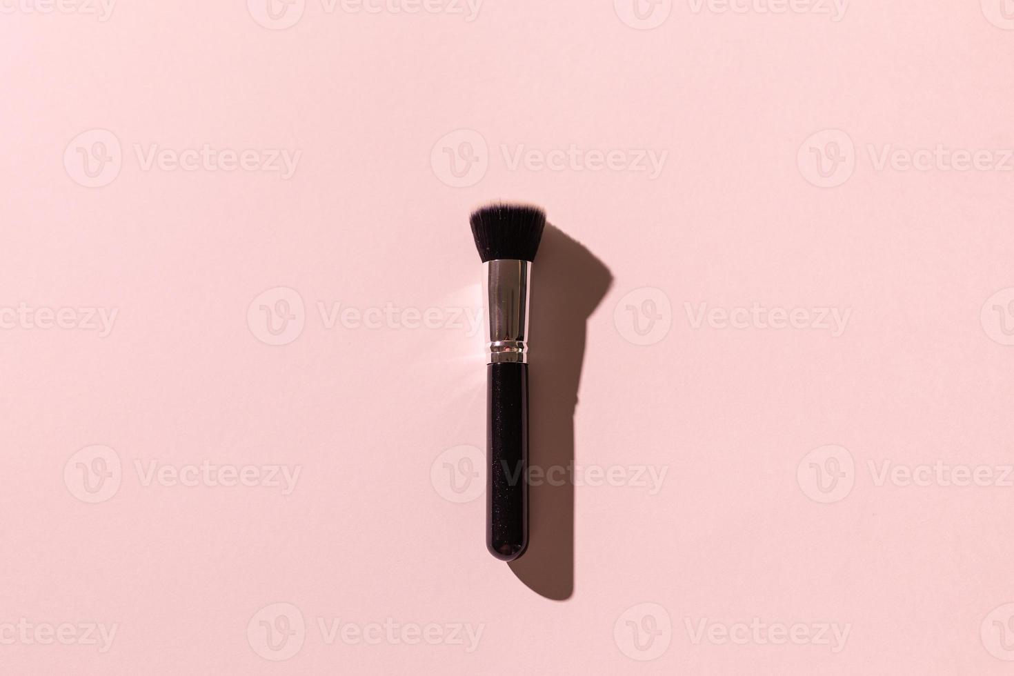 Make-up brush on pink background, top view. Cosmetics and beauty concept. photo