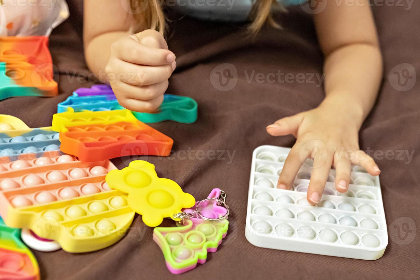 pop it es un juguete antiestrés multicolor en las manos de los niños. juego de burbujas juguetes antiestrés. foto