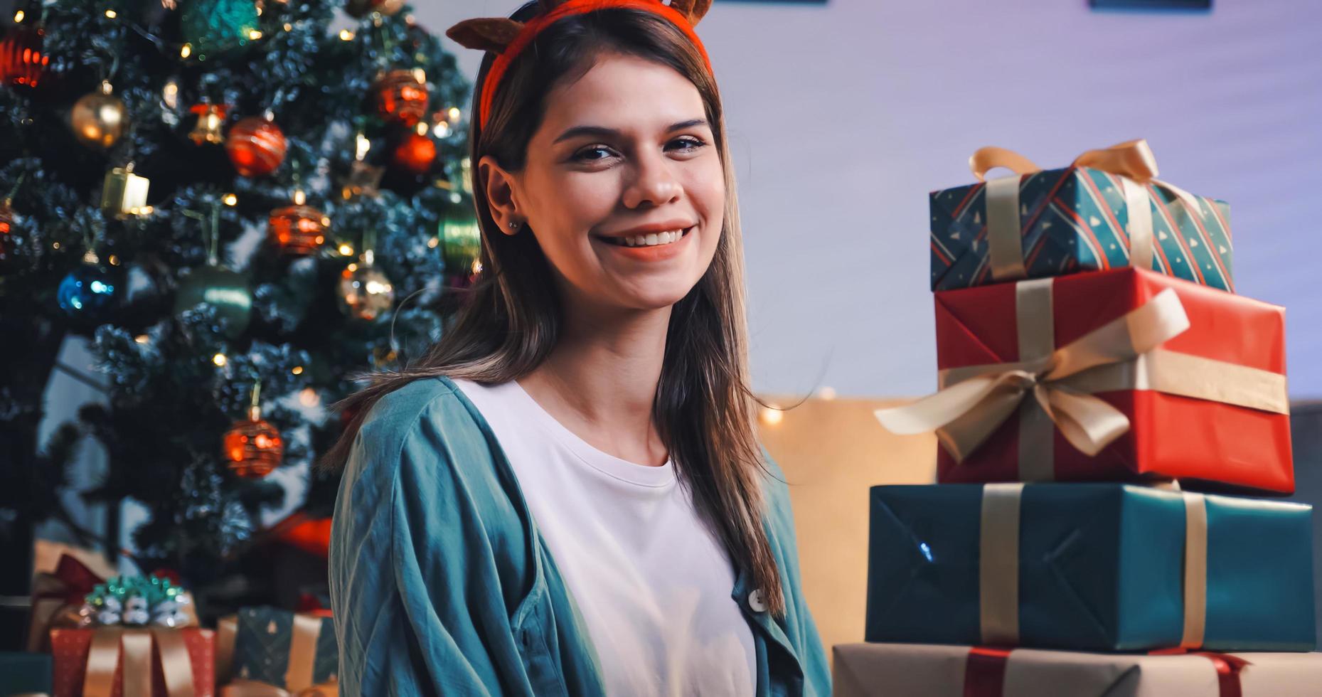 Beautiful young woman preparing presents for friends at Christmas party at home. photo