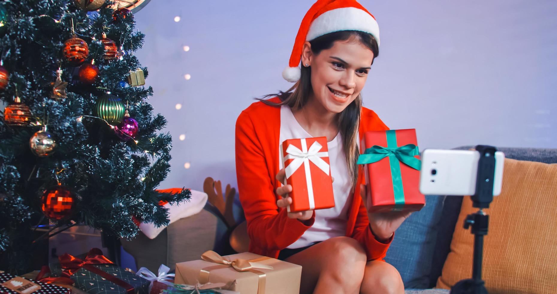 Beautiful young woman on video call invites her friends to Christmas party at her home. photo