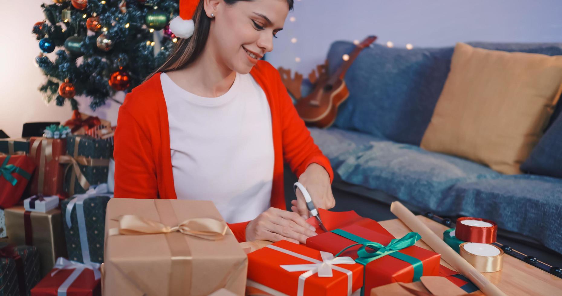 Beautiful young woman preparing presents for friends at Christmas party at home. photo