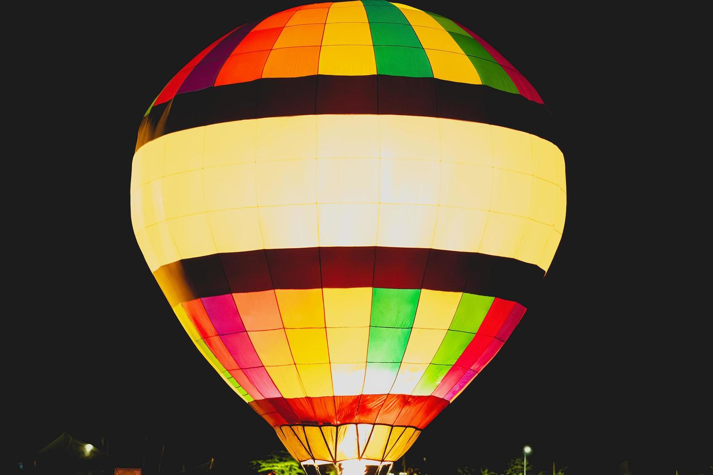 Close-up shot of bright and beautiful red, blue, yellow, and orange balloons rising in the night sky with a black background. photo