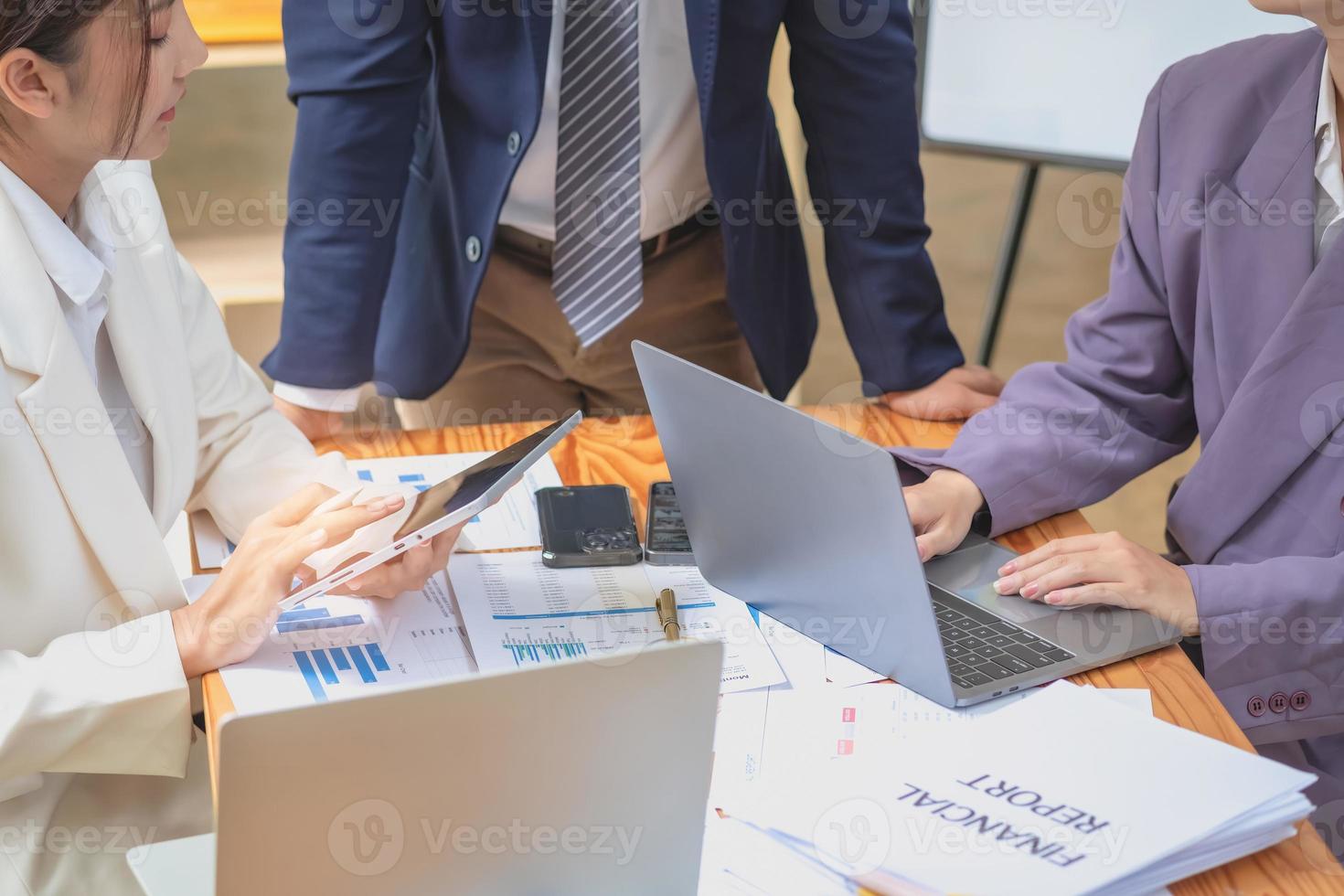 Asian business team consists of marketing staff. accountant and financial officer Help each other analyze company profits using tablets. calculator Laptop computers, graph paper, and corporate pens. photo