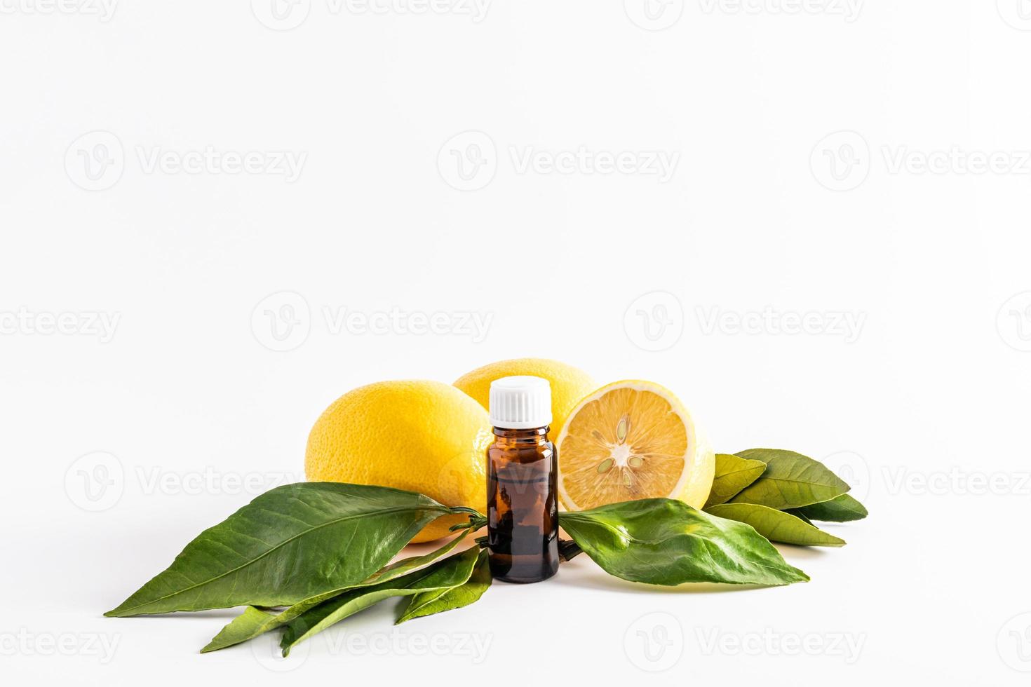 medical bottle made of dark glass with a white cork on the background of ripe lemons and leaves. lemon essential oil. vitamin C. Spa, aromatherapy. photo