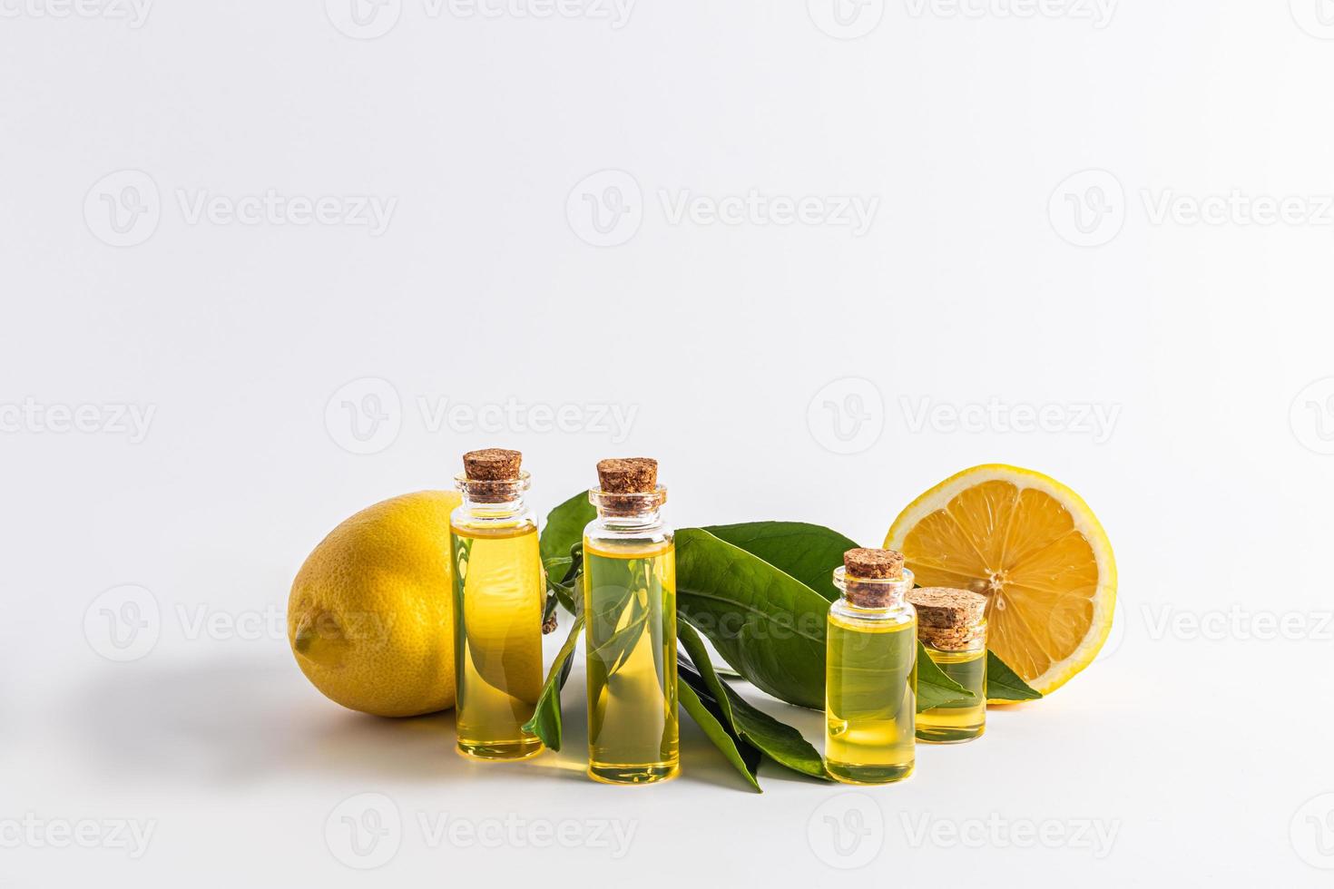 Various glass bottles with cork with organic lemon oil on a white background with ripe fruits. front view. natural care. photo