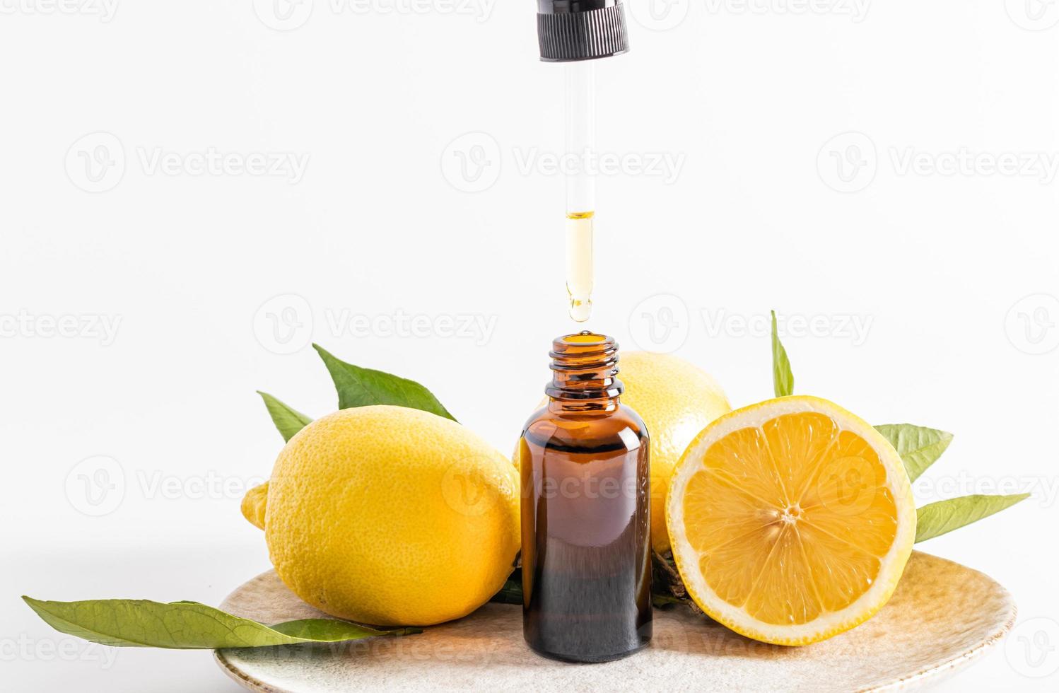 a natural organic facial skin care product based on lemon essential oil in a transparent bottle and pipette. white background. front view. photo