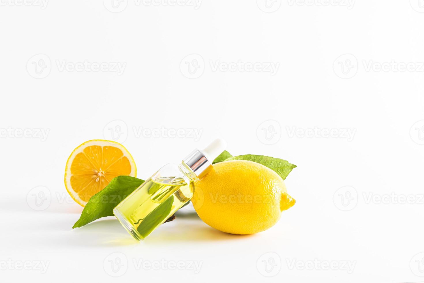 lemon serum for the face with vitamin C in a transparent bottle with a dropper lies on a ripe lemon. white background. front view. a copy space. photo