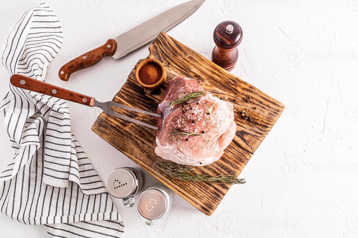 Fresh farm pork meat lies on a wooden textured board next to the spice containers for cooking. white background. top view. photo