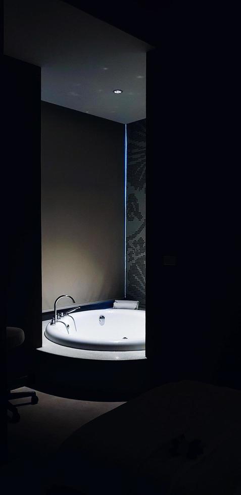 bañera blanca con luz en el baño y primer plano oscuro. diseño de interiores y concepto de objeto foto