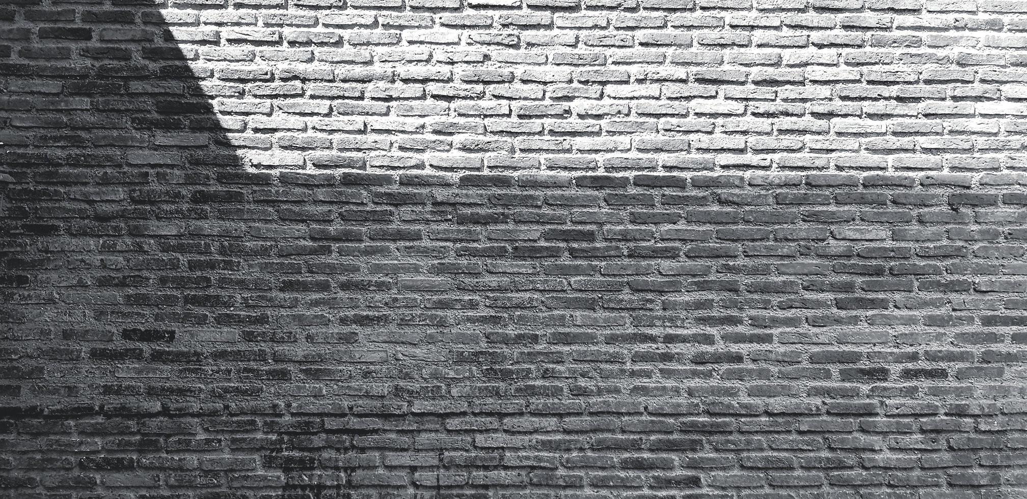 Brick wall with shadow for background in black and white tone. Art and Pattern wallpaper in monochrome style. Loft, Rough and Grunge exterior or interior design with copy space photo