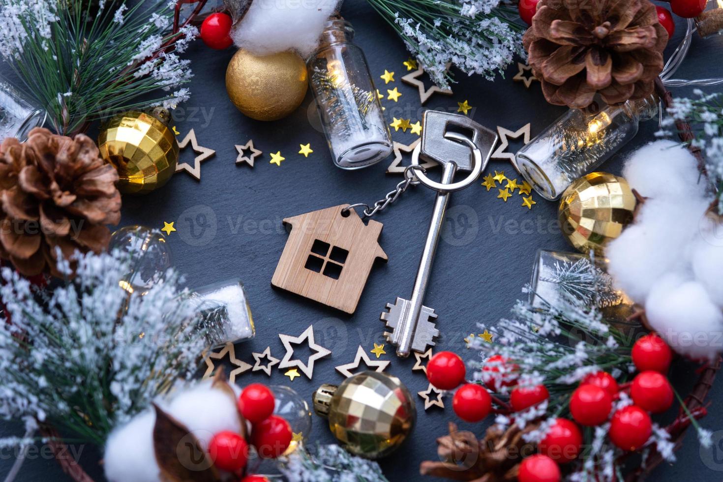 Key to the house with a keychain on black background with Christmas decor layout. A gift for New Year, Christmas. Building, design, project, moving to new house, mortgage rent and purchase real estate photo