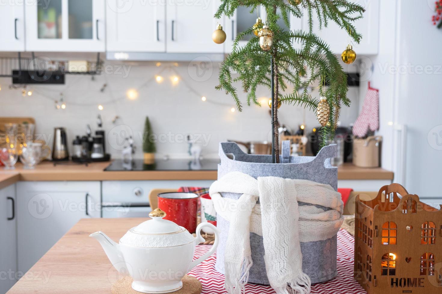 Festive Christmas decor in white kitchen, festive breakfast, white scandi interior. Araucaria as a Christmas tree is decorated and wrapped in a scarf and felt planters. New Year, mood, cozy home photo