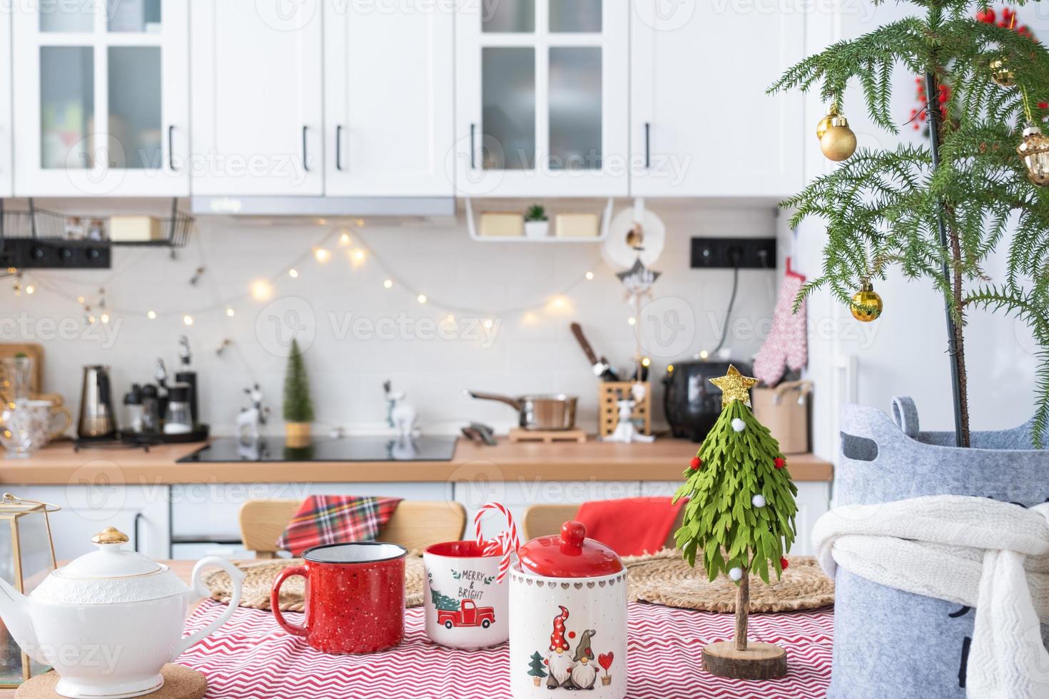 Festive Christmas decor in white kitchen, festive breakfast, white scandi interior. Araucaria as a Christmas tree is decorated and wrapped in a scarf and felt planters. New Year, mood, cozy home photo