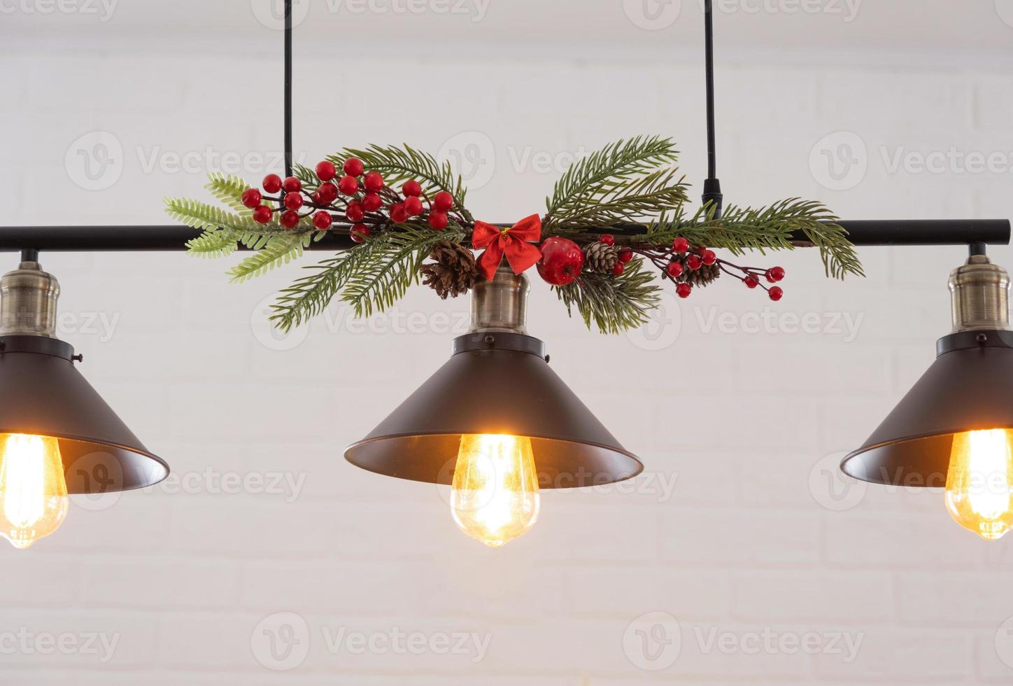 The black lampshade in the industrial loft style is decorated with spruce branches for Christmas and New Year on the background white brick wall. Close-up, minimalism photo
