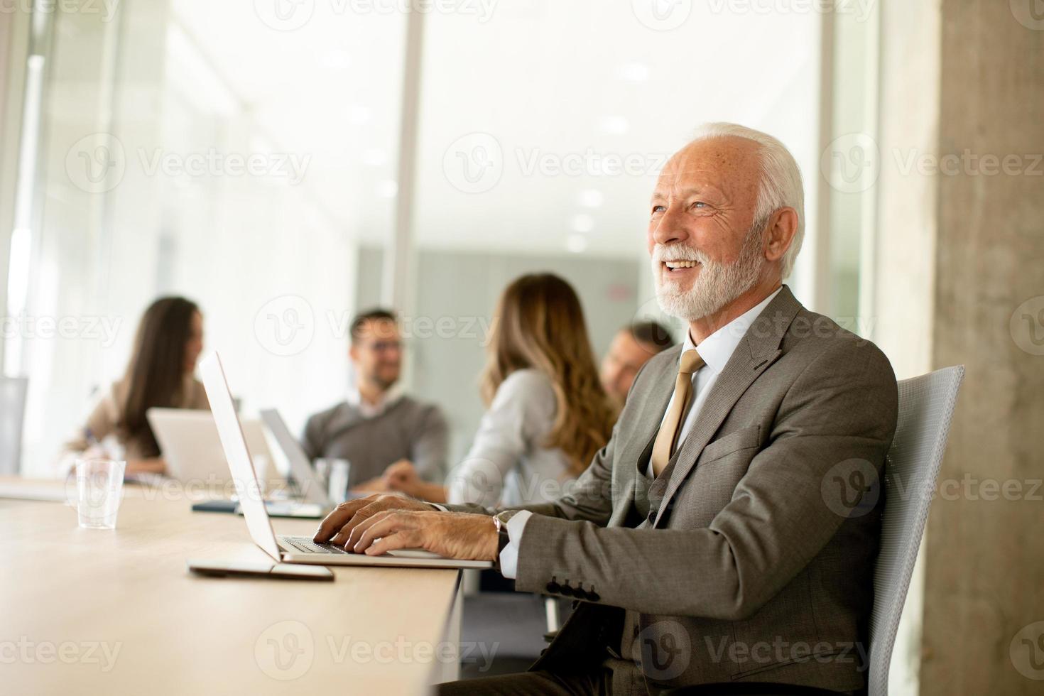 hombre de negocios senior que trabaja en una tableta digital en la oficina foto