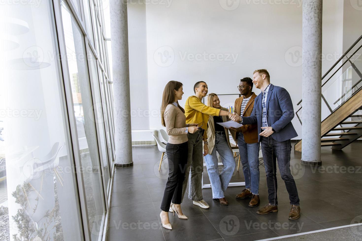 Memembers of creative team shaking hands while working in the modern office photo