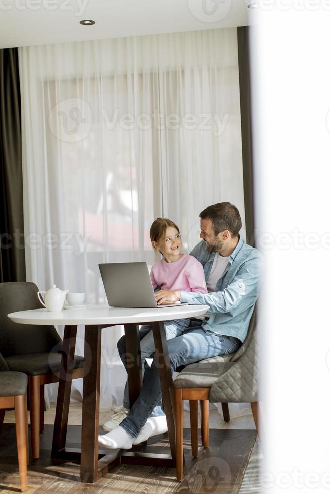 Father and daughter using laptop computer together photo