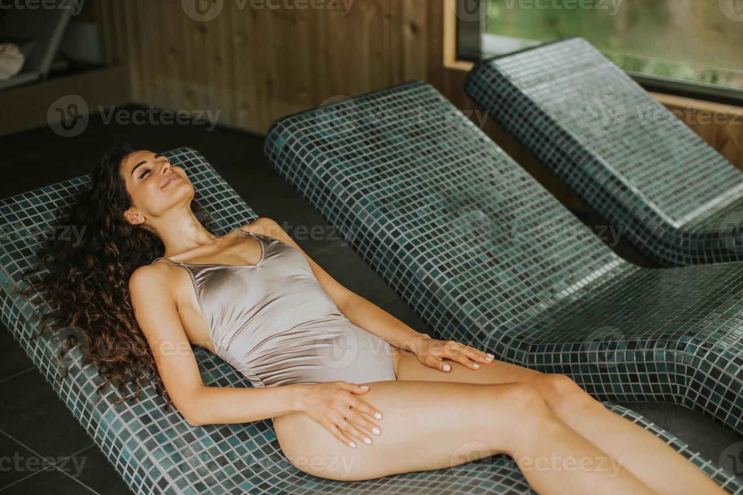 mujer joven relajándose en la cama tepidarium en el spa foto
