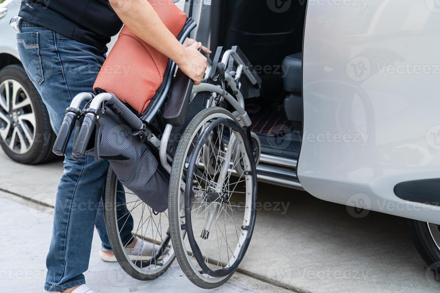 Asian woman folding and lift up wheelchair into her car. Accessibility concept. photo