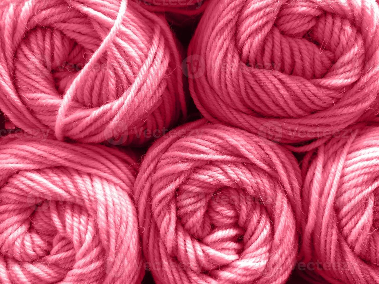 Wool yarn skeins are folded in stacks, close-up texture. Photo toned in color of the year 2023 viva magenta.