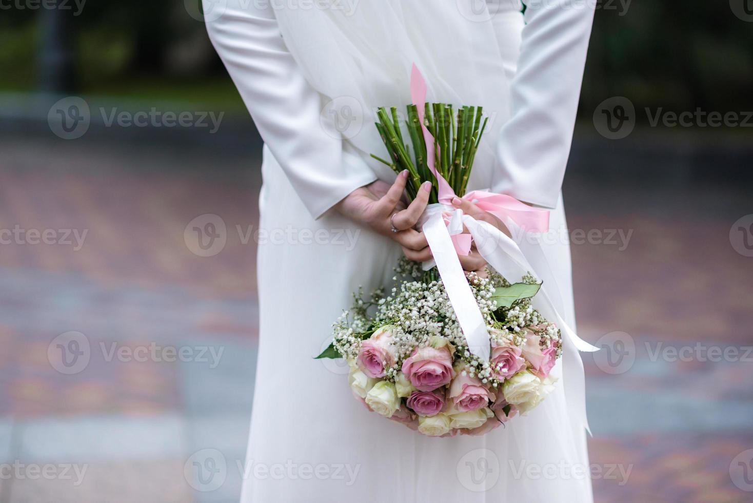 la novia con un vestido de novia blanco sostiene un ramo de flores blancas: peonías, rosas. boda. la novia y el novio. delicado ramo de bienvenida. hermosa decoración de bodas con hojas foto