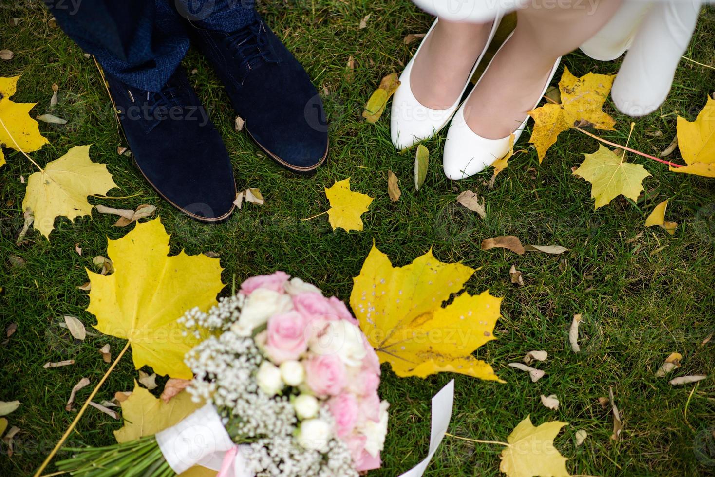 foots of bride and groom . The bride and groom holding on hands and walking on road in the nature. Outdoors. Down view at shoes. photo