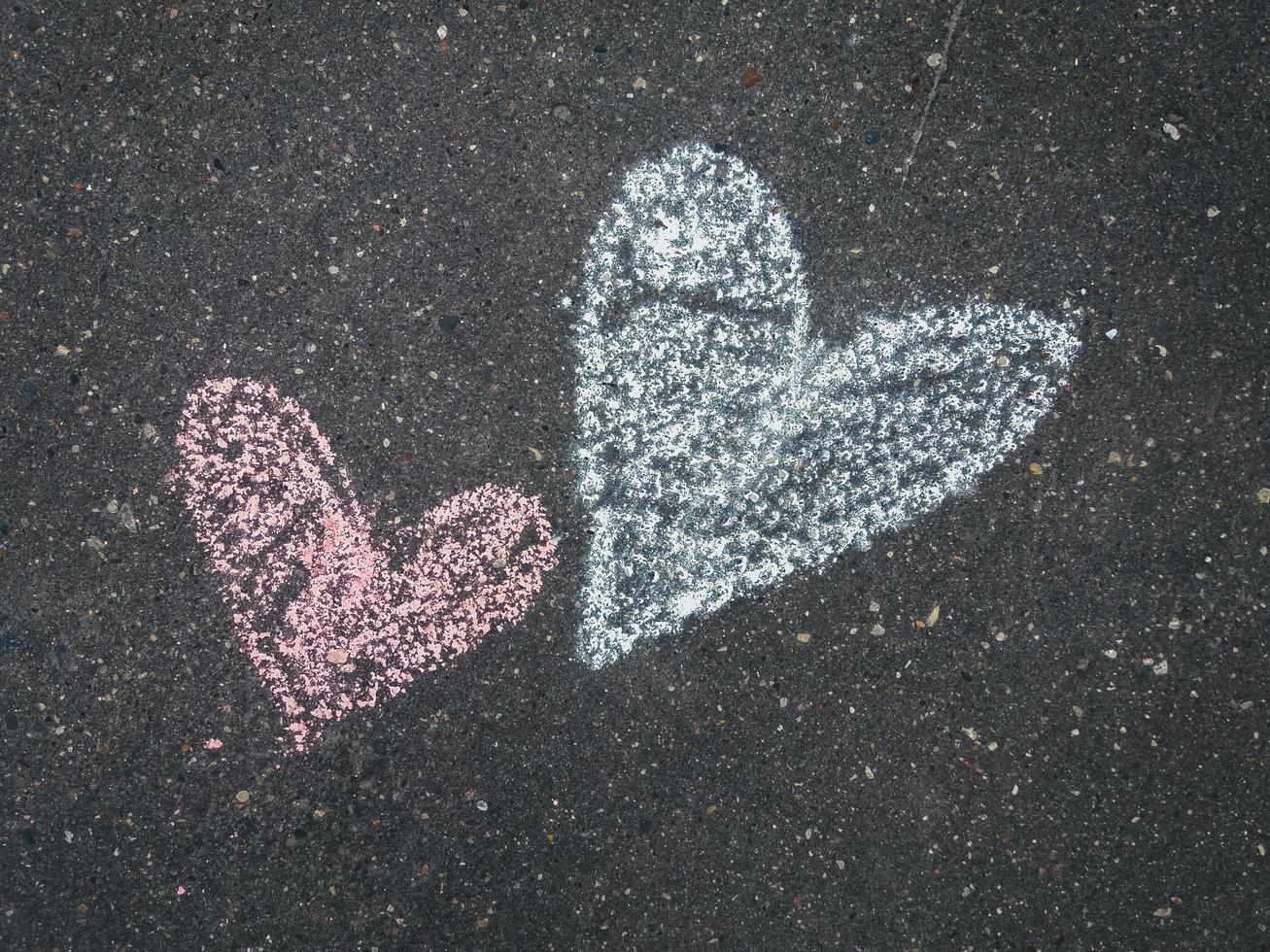 Two chalk drawn hearts on the asphalt, closeup photo