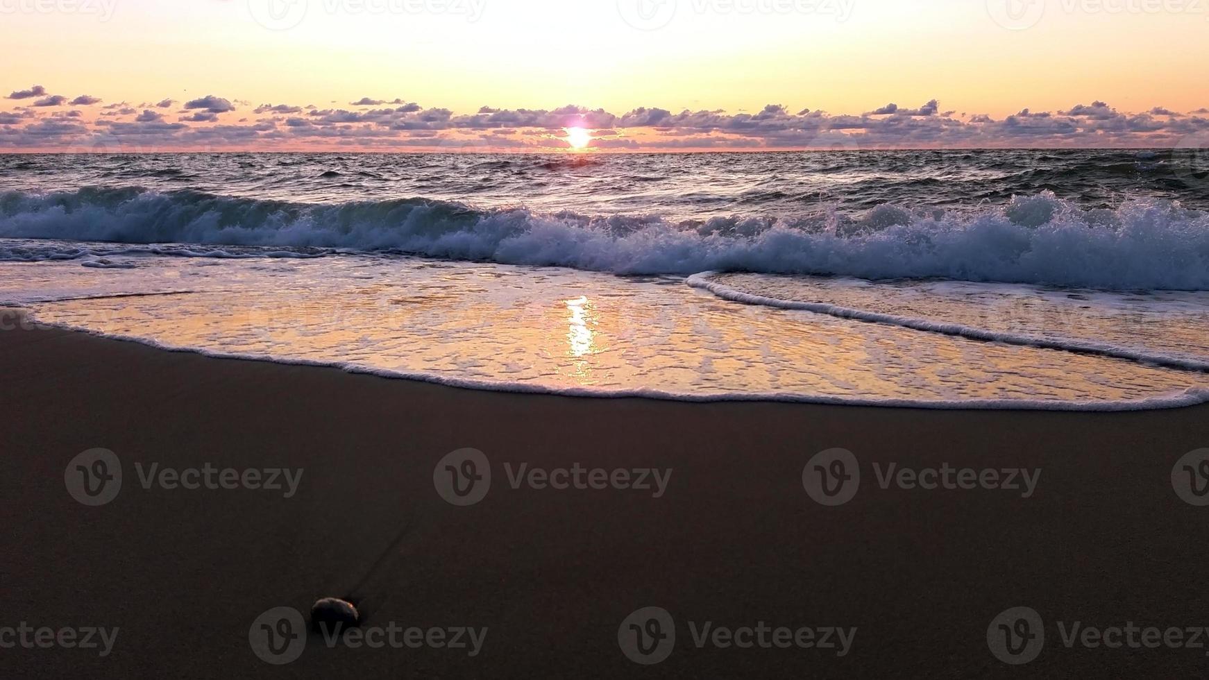 mar tormentoso por la noche, nubes bajas, sol poniente sobre el báltico al final del día ventoso foto