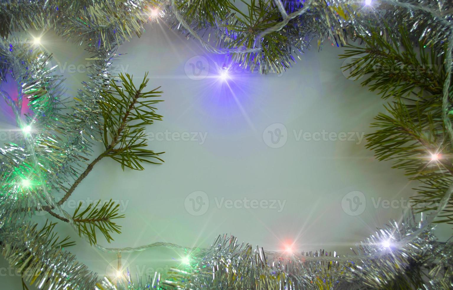 Christmas background. Christmas tree branches, light garland and tinsel. photo