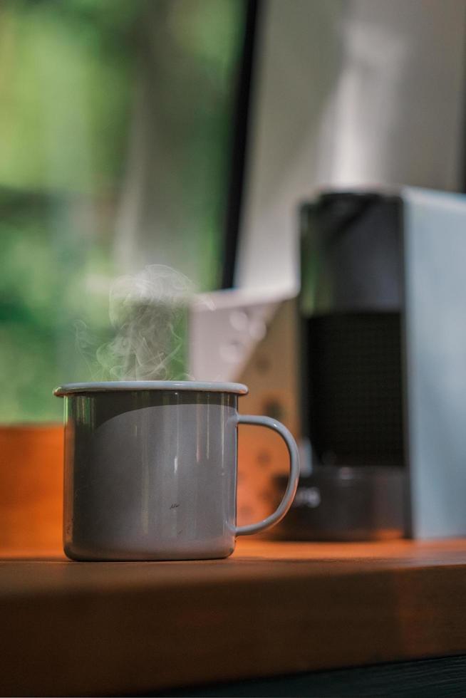 Steaming cup of coffee on the window sill of a campervan - Van Life and Slow living photo