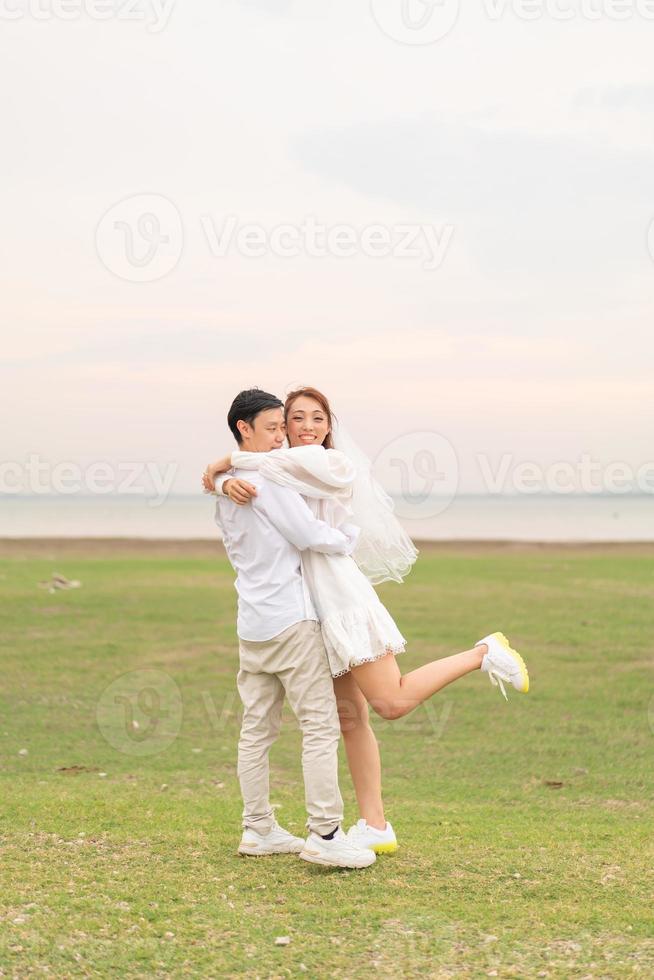 Happy young Asian couple in bride and groom clothing photo