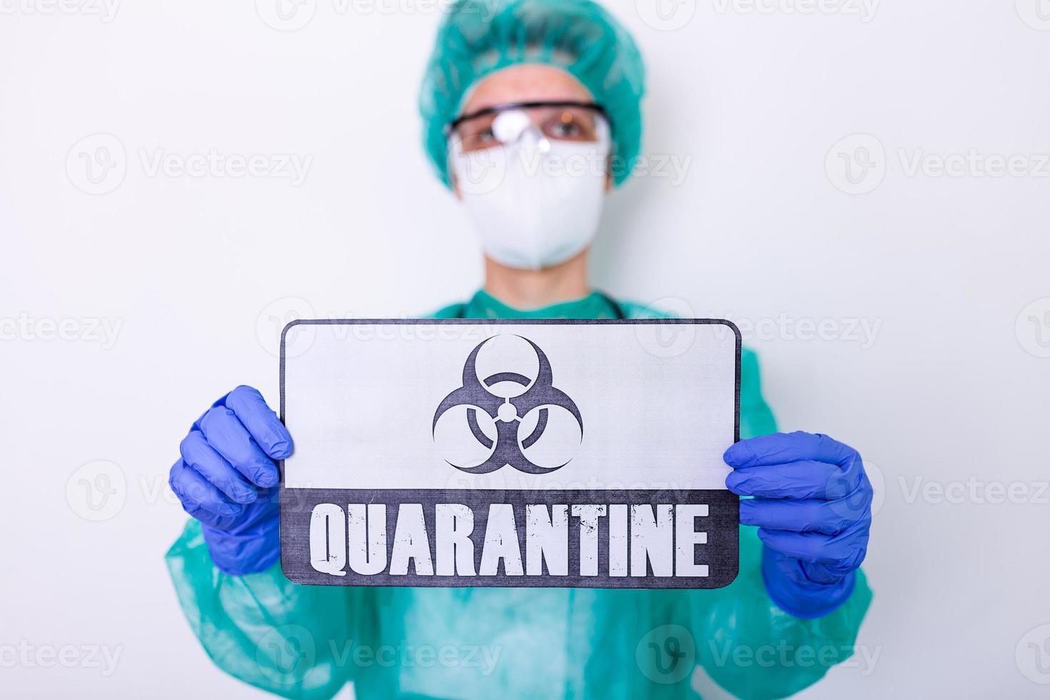 Coronavirus COVID 19 doctor in isolation holding sign for Corona Virus Quarantine. Quarantine alert sign in hospital with blurred doctor with mask and protective suit. Corona virus outbreak photo