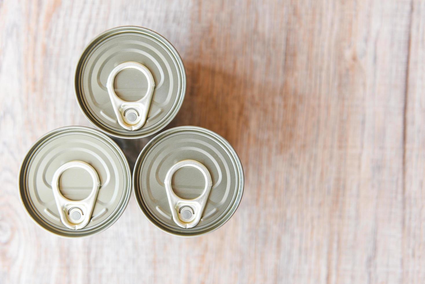 Canned food in metal cans on wooden background , top view canned goods non perishable food storage goods in kitchen home or for donations photo