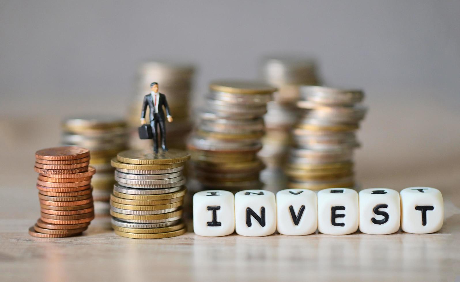 invest message and business man standing on a coin on wooden table background, invest business economy concept of money and finance investments photo