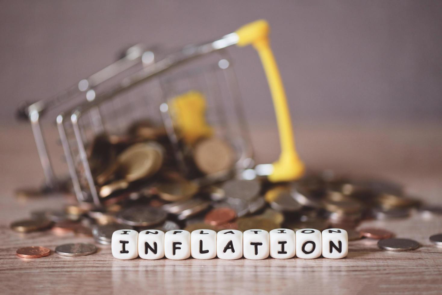 inflation with coin and shopping cart on wooden background, business economy inflation concept of money and finance - Rising grocery prices and surging cost more expensive things photo