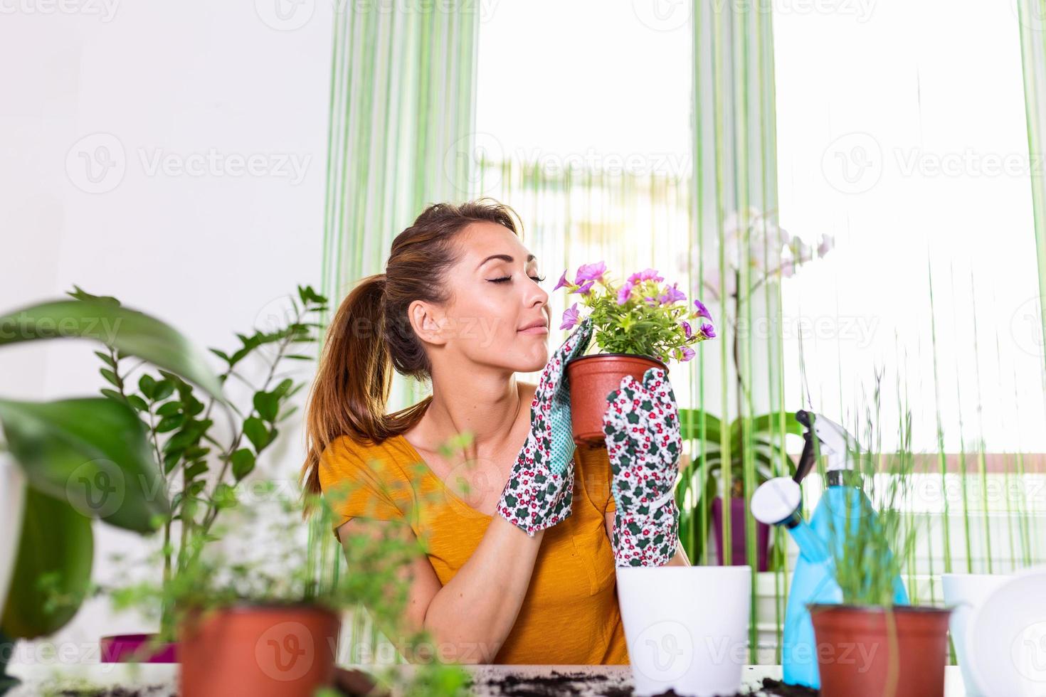 Lovely housewife with flower in pot and gardening set. Work at home. Planting a flower and spring cleaning. The housewife changes ground for a plant. Care for a potted plant photo