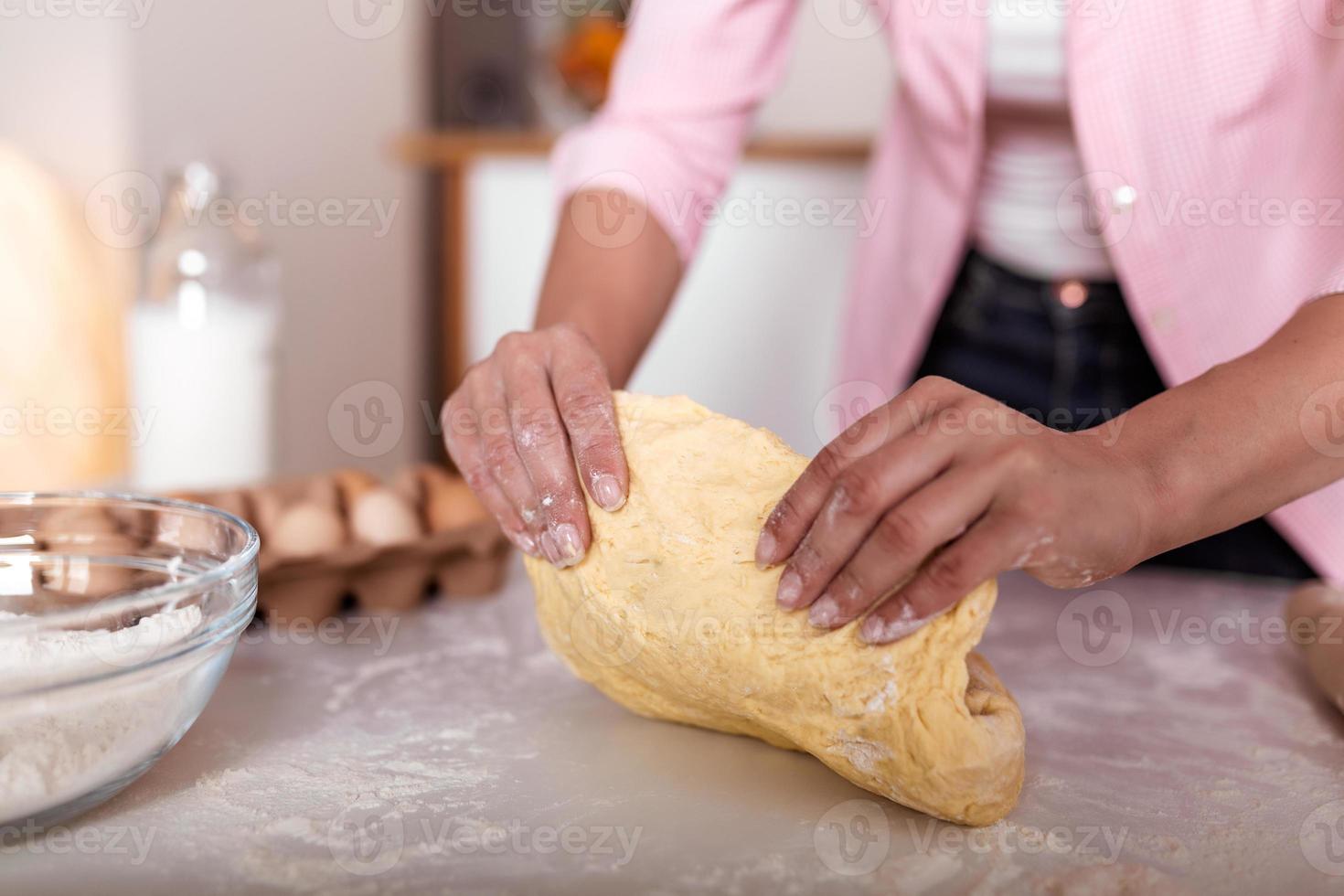 Close up of female baker hands kneading dough and making bread. cooking and home concept - close up of female hands kneading dough at home photo