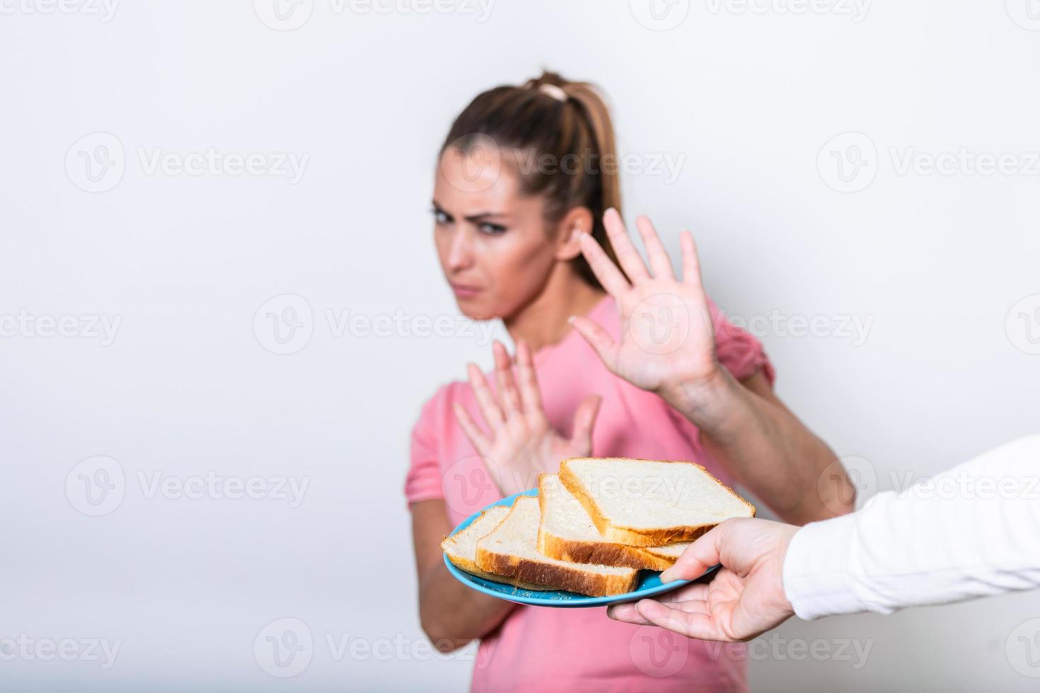 Young woman suffers from a gluten. Gluten intolerant and Gluten free diet concept, Real people. Copy space. Gluten intolerance and diet concept. Woman refuses to eat white bread. Focus on bread photo