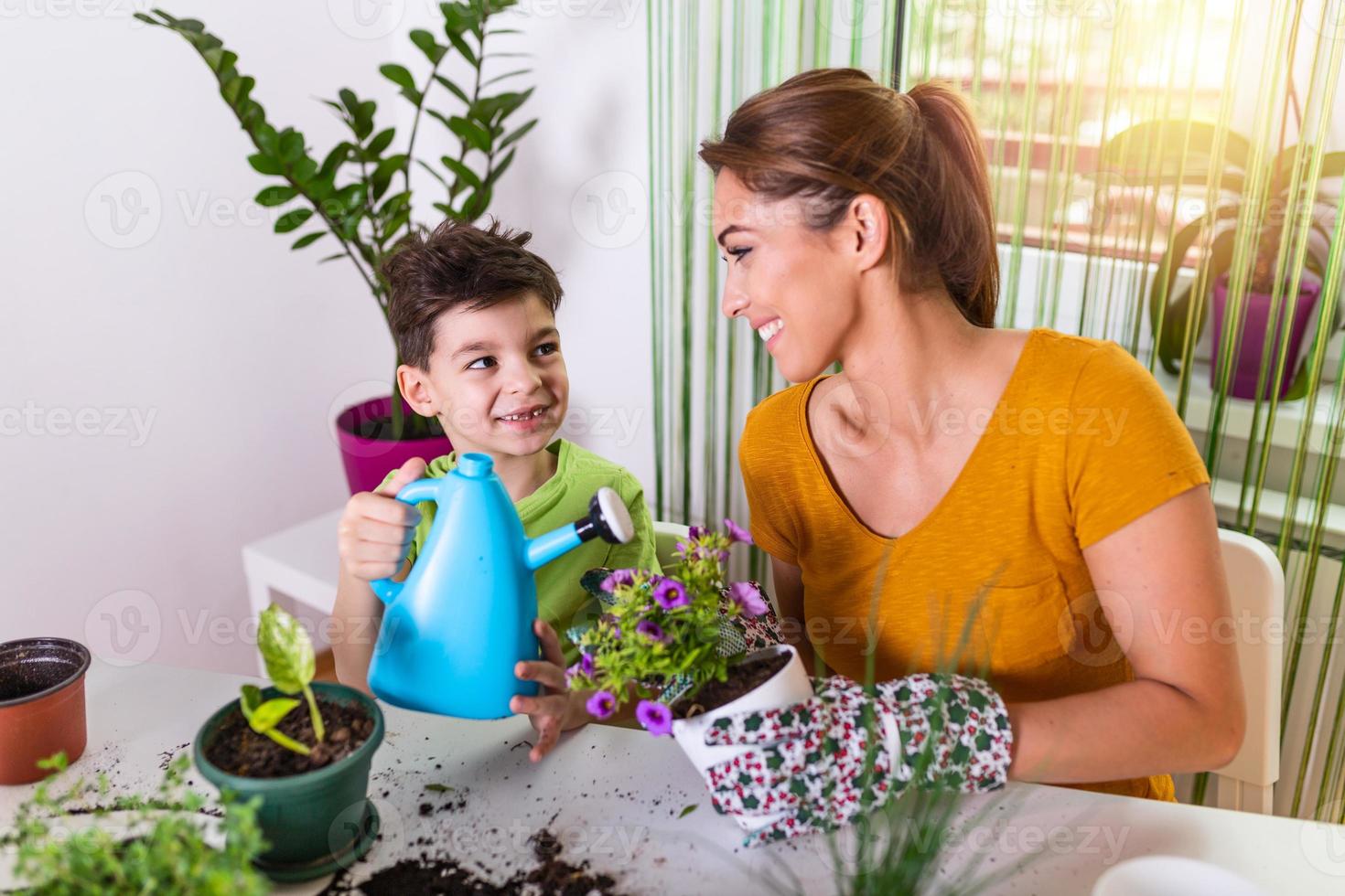mamá y niño riegan las plantas juntos, la pequeña asistente de jardinero de mamá, cuida de los niños y las flores. chico lindo regando de la regadera, cuidando árboles y plantas, niño mojado foto