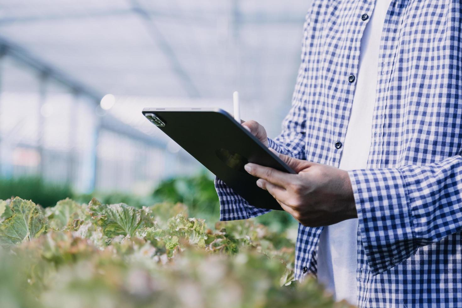 Futuristic businessman farms vegetables and crops using modern AI technology using mobile phones, temperature and humidity sensors, water tracking, climate control, holographic data data icons. photo