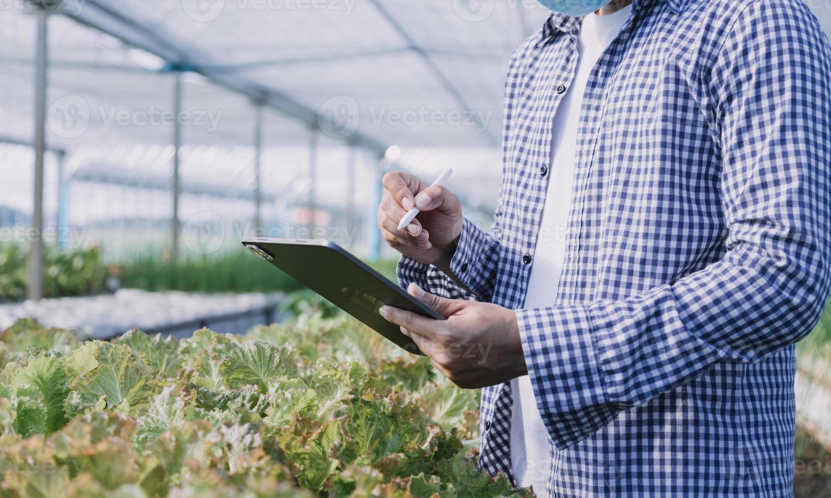 Futuristic businessman farms vegetables and crops using modern AI technology using mobile phones, temperature and humidity sensors, water tracking, climate control, holographic data data icons. photo